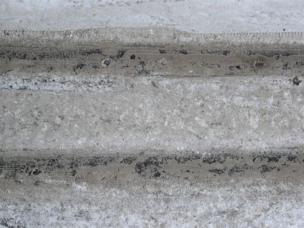 Texture of road in white snow with tire marks and dirty surface.